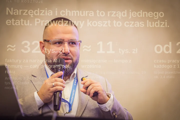 Prelegent z mikrofonem na tle prezentacji